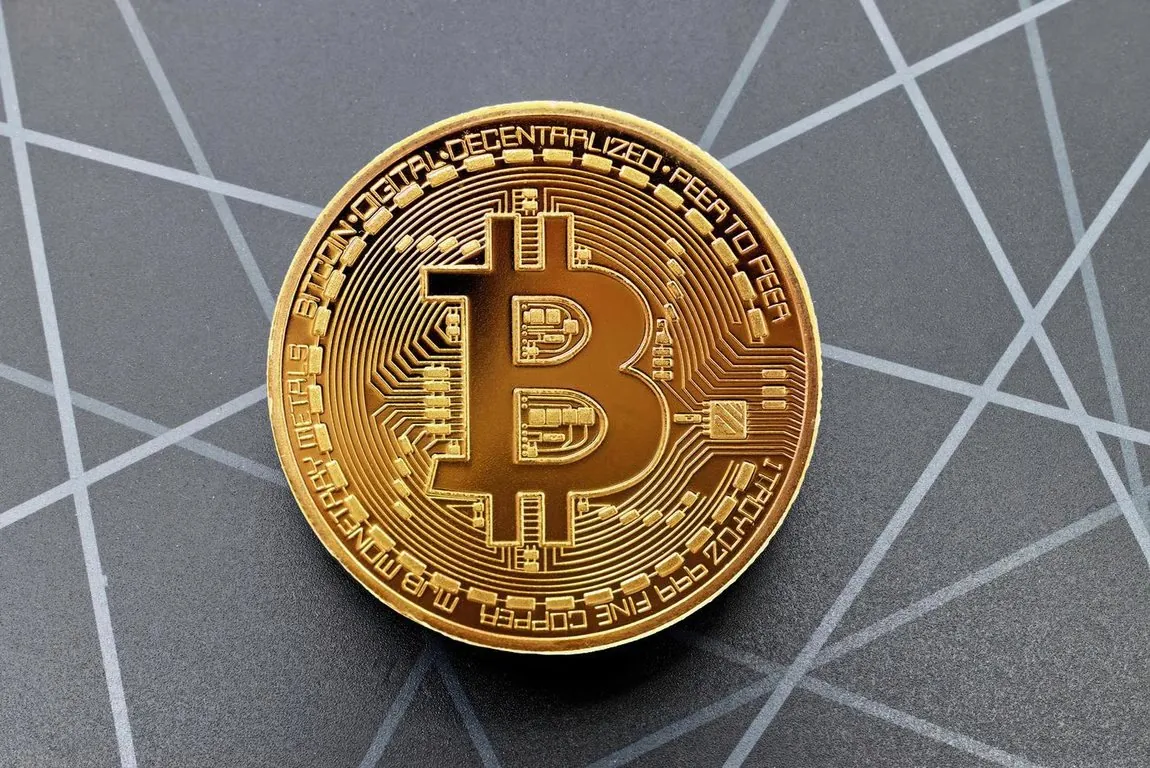 Ilustrasi koin Bitcoin berwarna emas di atas pola garis.