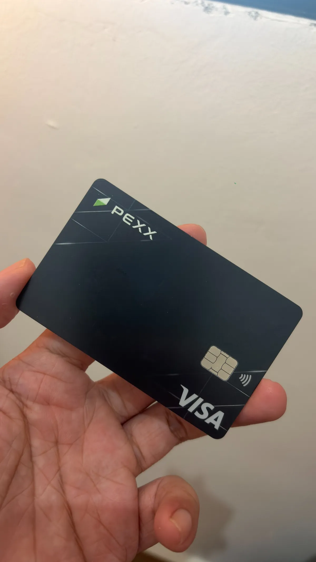 Kartu fisik PEXX Visa berwarna hitam yang dipegang paman.