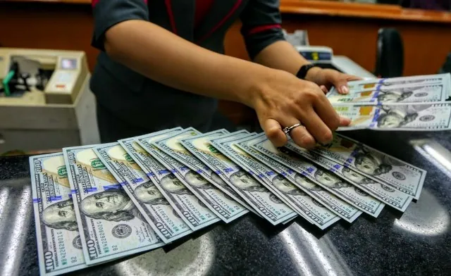 Petugas menghitung lembaran uang dolar Amerika Serikat.